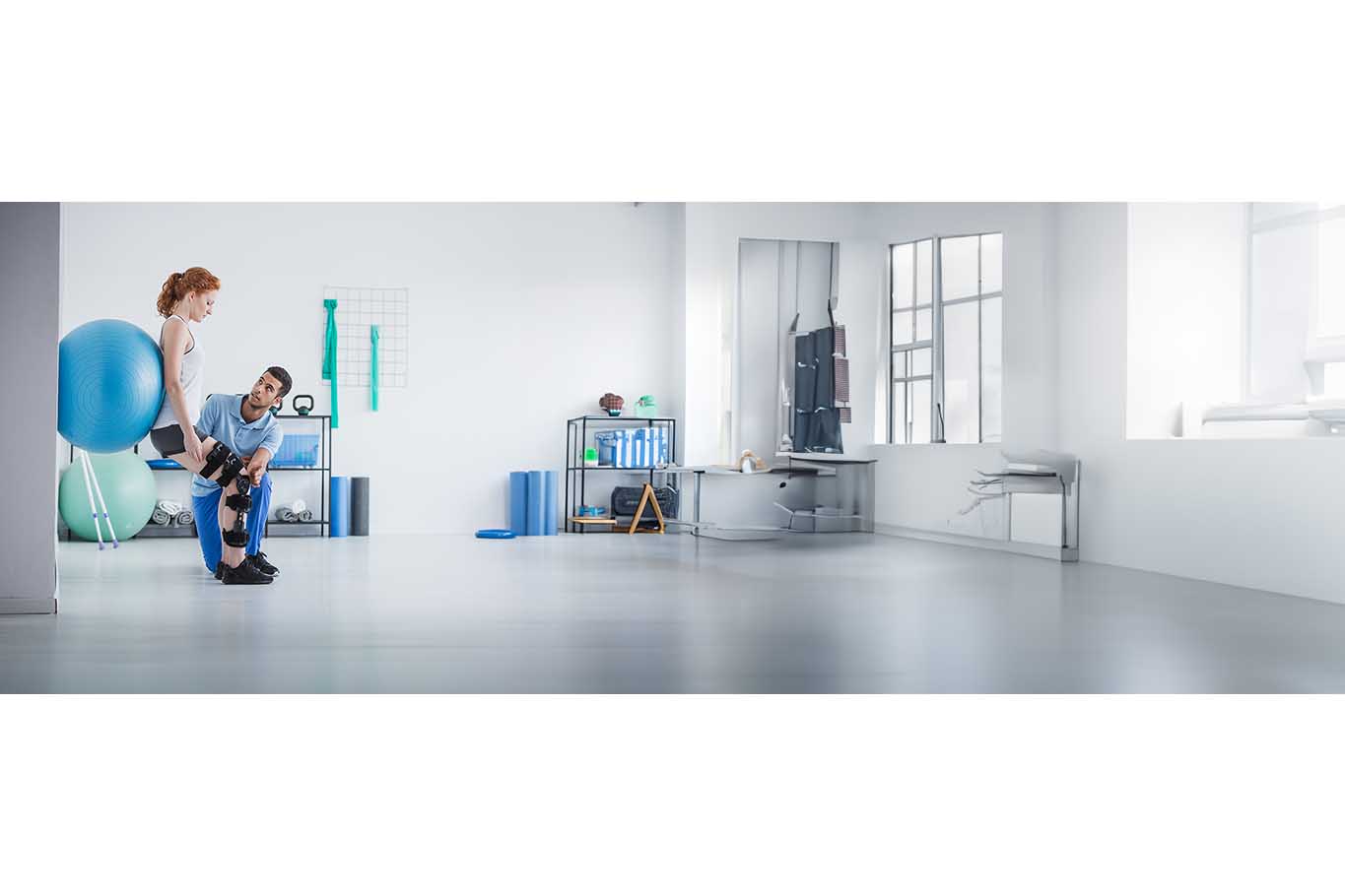 A man and woman in a modern gym setting, with exercise equipment and a clean, contemporary interior.